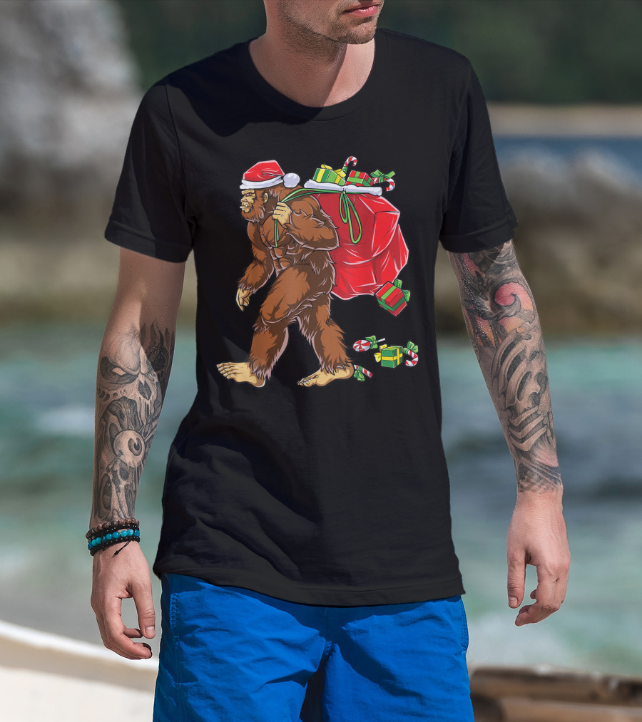 Bigfoot Santa With Giant Red Christmas Bag And Green Gifts Wearing Xmas Hat T-Shirt