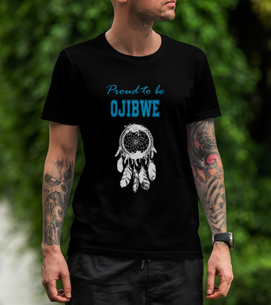 Man with tattoos models Proud to Be Ojibwe White Dreamcatcher T-Shirt outdoors.