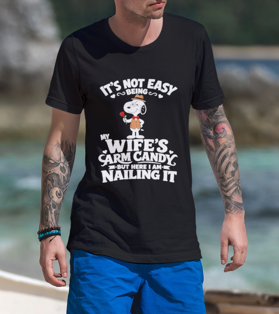 Snoopy It's Not Easy Being My Wife's Arm Candy But Here I Am Nailing It T-Shirt