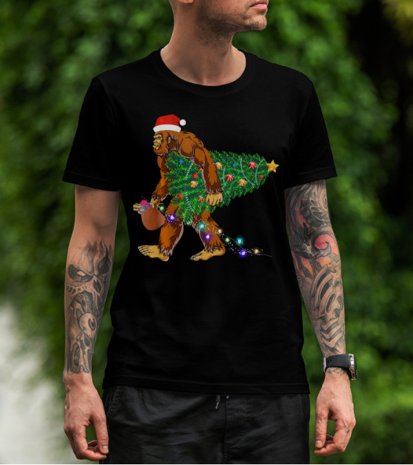 Santa Hat Bigfoot Holding Christmas Tree With Lights And Gifts T-Shirt